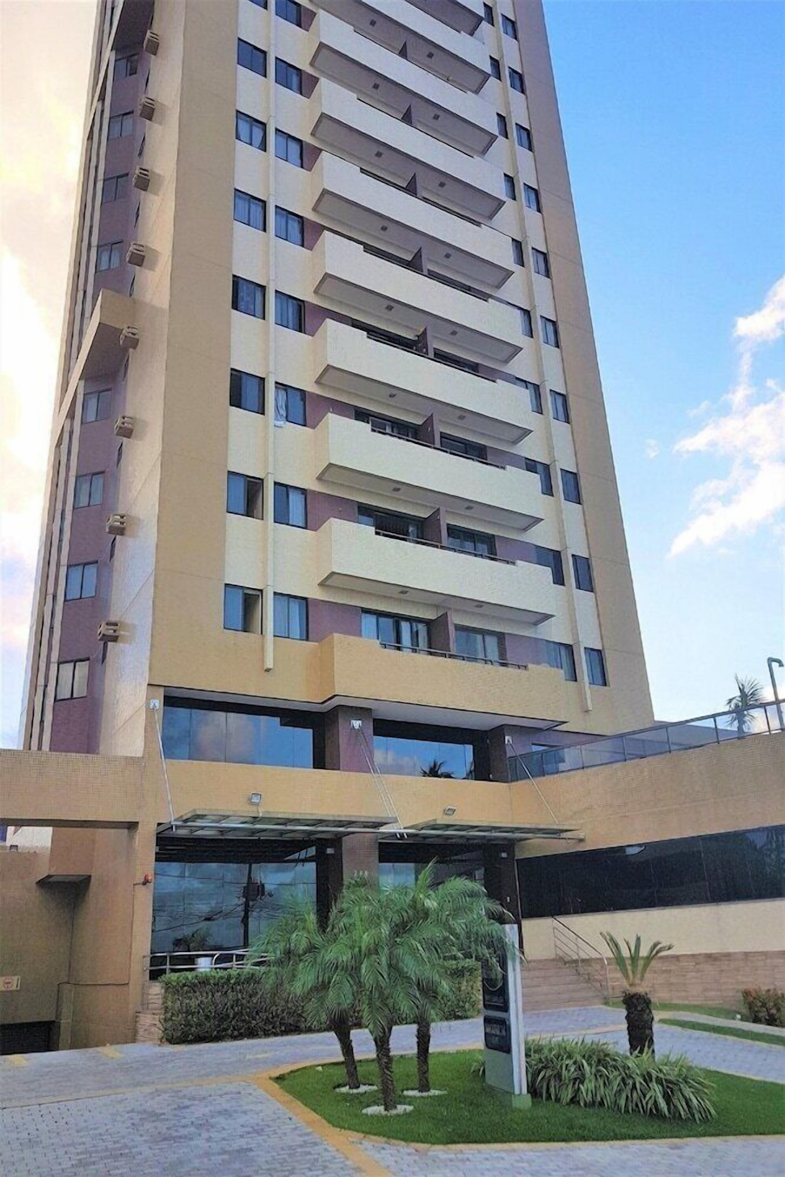 A tall, modern building with multiple balconies and a covered entrance area.