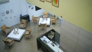 Un salón de conferencias con una mesa blanca, varias sillas, una vitrina de vidrio y un escritorio para computadora.