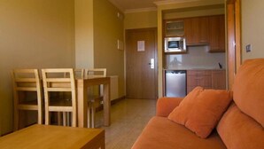 A compact living space with a kitchenette, a wooden dining table, and a sofa. - Esperanza del Mar Apartments (Sanxenxo)