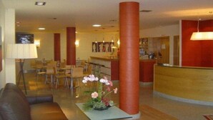 A hotel lobby with a reception desk, seating area, and a dining section. - Esperanza del Mar Apartments (Sanxenxo)