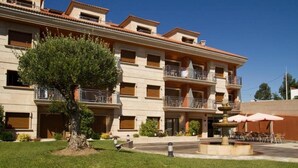A multi-story hotel with balconies, a central courtyard with a fountain, and outdoor seating. - Esperanza del Mar Apartments (Sanxenxo)