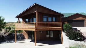 A modern wooden cabin with a balcony, a garage, and a landscaped garden.