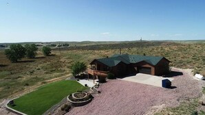 A log cabin with a large front porch, a garage, and a well-maintained lawn.