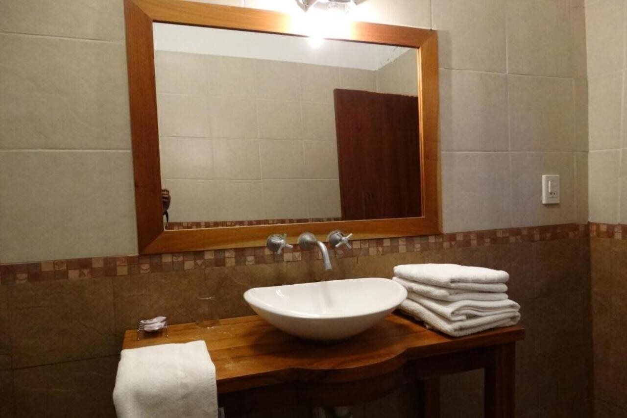 A bathroom with a wooden vanity, a white sink, and a mirror.