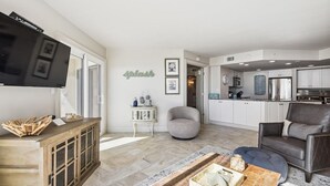 Ein modernes Wohnzimmer mit Fernseher, Holzschrank, grauem Sessel und Couchtisch.