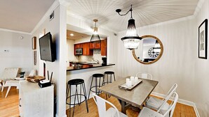 Una cucina moderna con mobili in legno, un'area pranzo con tavolo in legno e sedie bianche, e un grande lampadario.