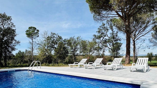 Una piscina con sillas de descanso blancas y una escalera metálica.
