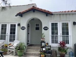 Stucco exterior home with a central entrance, porch, and potted plants.