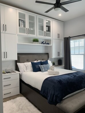 Cozy retreat with a central bed, white cabinet, and nightstand, perfect for a restful stay.