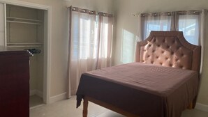 Une chambre à coucher avec un lit, une armoire et une fenêtre avec des rideaux.