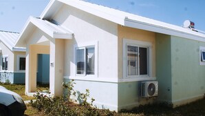 Il s’agit d’un bâtiment d’un seul étage, doté d’un toit plat, d’un petit garage attenant et d’un appareil de climatisation fixé au mur extérieur.