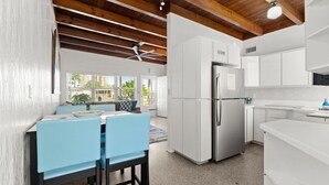 Een moderne keuken met witte kasten, een roestvrijstalen koelkast en een eethoek met blauwe stoelen.