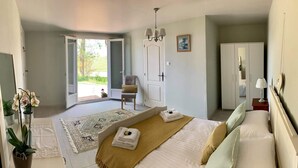 A bedroom with a bed, a chair, a wardrobe, and a door leading to a balcony. - Spacious gite with large heated private swimming pool and new hot tub. (Salerm)