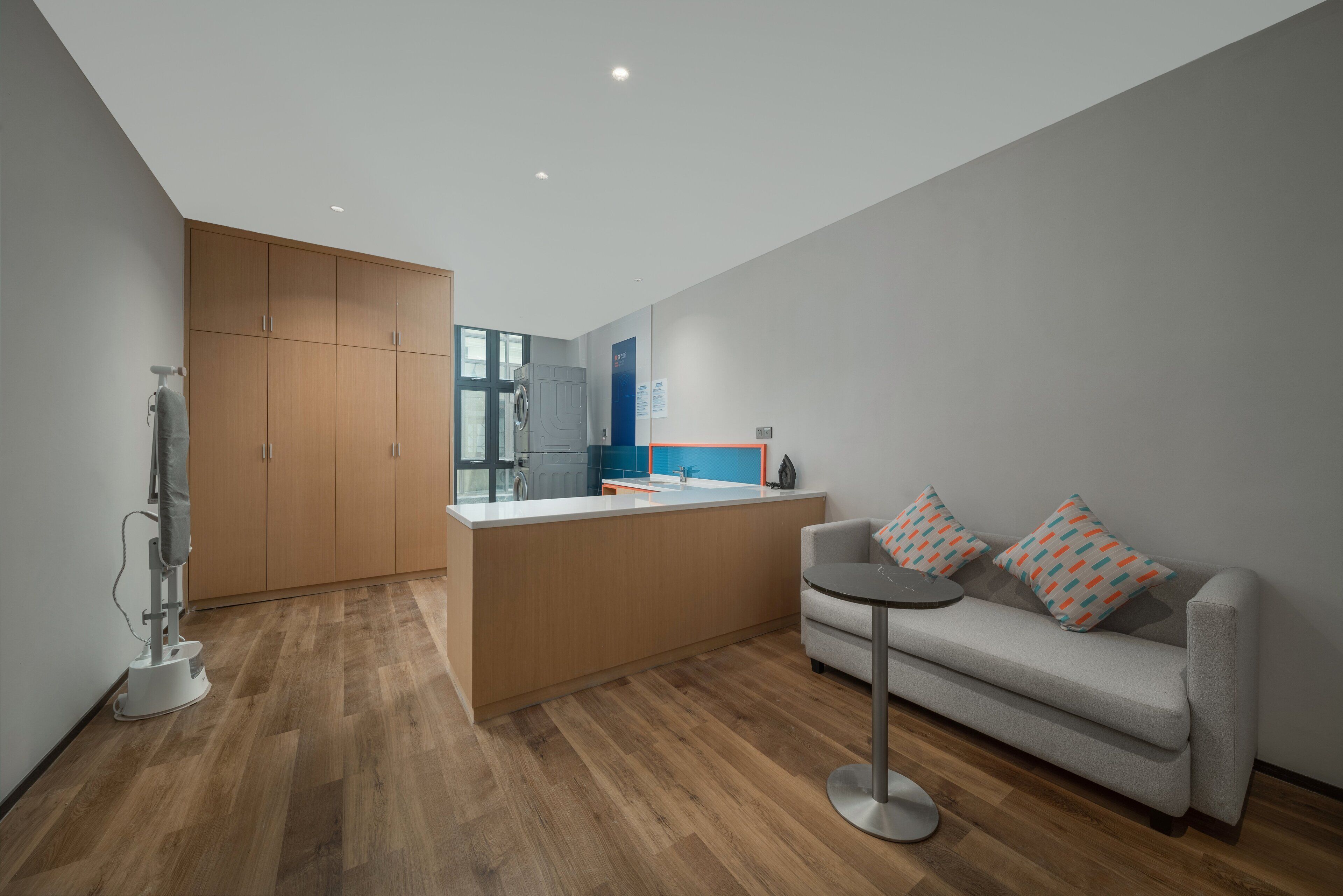 Una cocina moderna con armarios de madera, una isla central y un sofá gris con cojines estampados.
