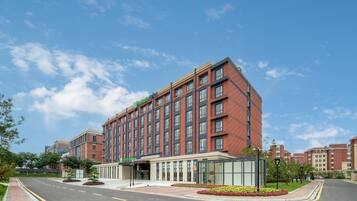 A modern hotel with a brick facade, large windows, and a landscaped entrance area.