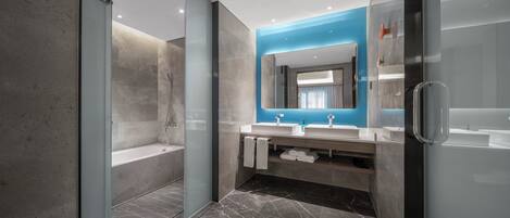 Un baño moderno con cabina de ducha de vidrio, tocador doble y un espejo grande.