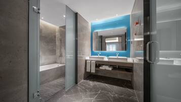 Une salle de bain moderne dotée d’une douche à parois de verre, de deux lavabos et d’un grand miroir.
