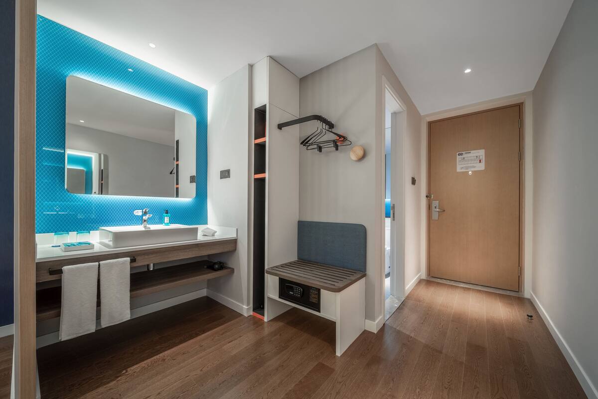 A modern bathroom with a large mirror, a sink, and a bench.