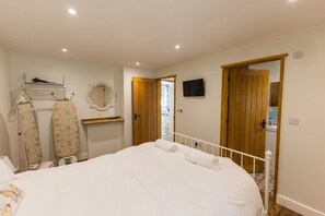 A bedroom with a bed, a mirror, a television, and a wardrobe. - Breckland Cottage - Secluded Country Getaway (Hockwold cum Wilton)