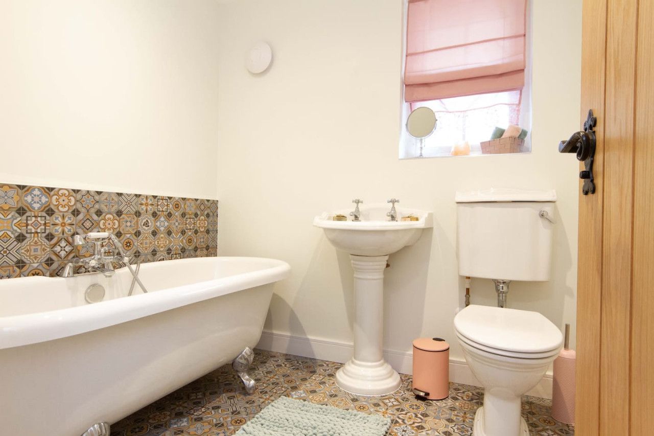 Un baño con una bañera independiente, un lavamanos pedestal y un inodoro.