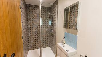 Ein Badezimmer mit Dusche, Waschbecken und Spiegel.