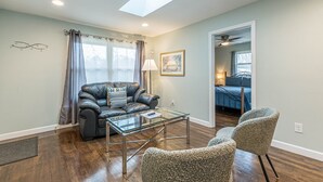 A living room with a glass coffee table, leather sofa, and two armchairs. - Welcome Home! 2BR with Driveway (Atlanta)