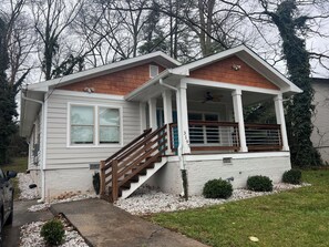 A single-story house with a covered porch, a staircase, and a small front yard.