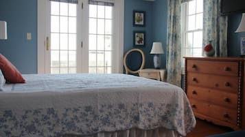 Un dormitorio con una cama grande, un aparador y dos ventanas con cortinas.