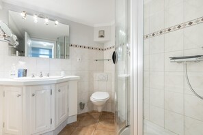 Ein Badezimmer mit weißem Waschtisch, Toilette und einer Duschkabine.