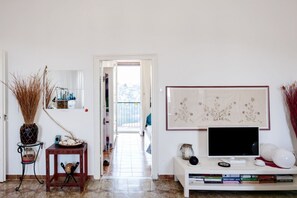 A living room with a TV, books, and a vase. - Bright apartment of about 85 square meters with balcony, which can accommodate up to 4 people, located on the first floor of a period building without lift. The property enjoys an excellent position, being situated in a panoramic area (sea view) and surr (La Spezia)