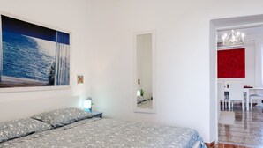 Un dormitorio con cama, un cuadro, un espejo y una zona de comedor con sillas.