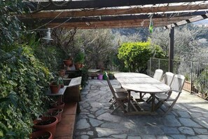 A stone patio with a wooden table and chairs, surrounded by potted plants and a pergola. - Bright apartment of about 85 square meters with balcony, which can accommodate up to 4 people, located on the first floor of a period building without lift. The property enjoys an excellent position, being situated in a panoramic area (sea view) and surr (La Spezia)