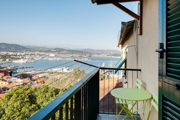 Ein Balkon mit Blick auf eine Küstenstadtlandschaft, darunter ein Yachthafen und Gebäude.