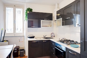 Una cocina moderna con armarios oscuros, una estufa a gas y un lavamanos.
