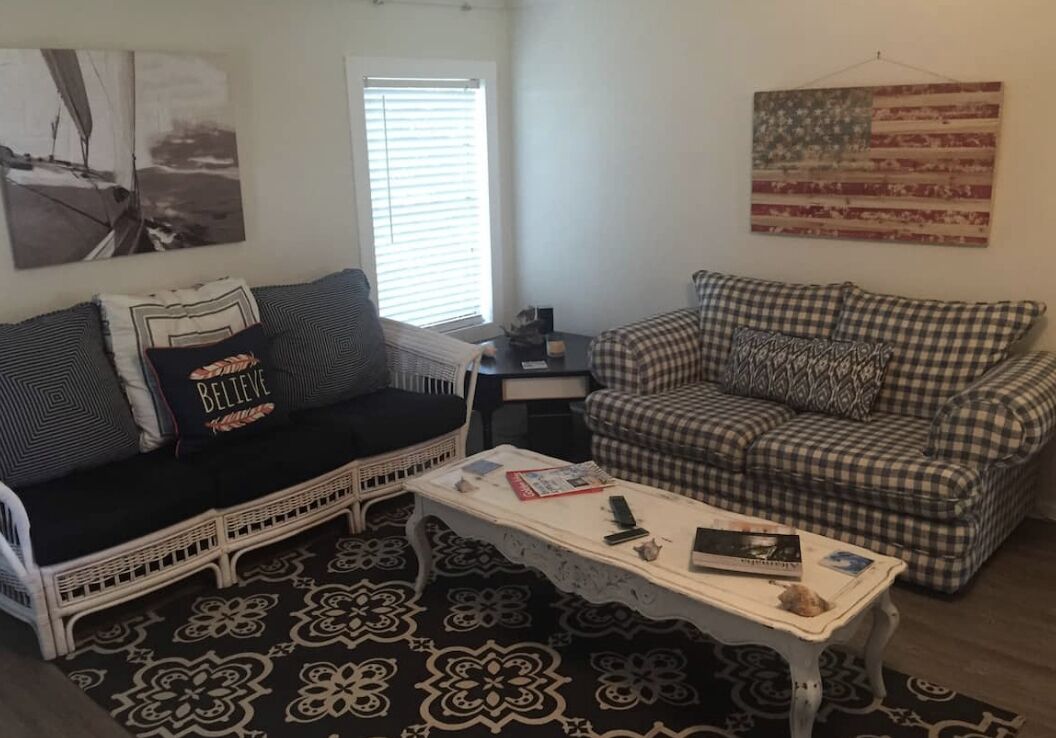 Uma sala de estar com dois sofás, uma mesa de centro e um tapete estampado.