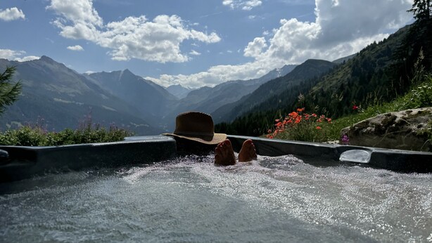 Une personne se détend dans un bain à remous avec vue sur les montagnes.