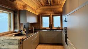 Une cuisine avec des poutres en bois au plafond, une fenêtre et un évier.
