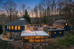 A large, multi-level house with a stone exterior, multiple decks, and outdoor seating areas.