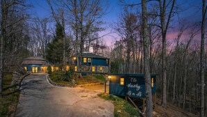 Una casa a due piani con tetto circolare, circondata da alberi e un vialetto che conduce all'ingresso.