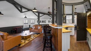 Spazioso loft con soffitto alto, travi a vista, zona salotto centrale con tavolino e cucina con bancone.
