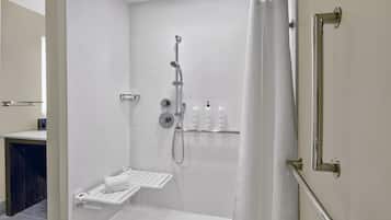 Um banheiro moderno com chuveiro, um porta-toalhas branco e uma prateleira com artigos de higiene pessoal.