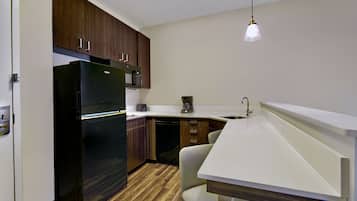 A compact kitchen with a built-in refrigerator, microwave, and coffee maker.