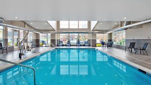 An indoor swimming pool with clear water, surrounded by lounge chairs and a view of the outside. - Residence Inn by Marriott Reading (Wyomissing)