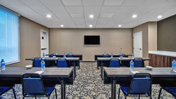 Una sala conferenze con pavimento in moquette, un televisore a schermo piatto montato a parete e tavoli con sedie.