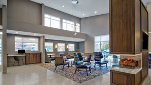 A spacious lobby with a high ceiling, large windows, and a central seating area with multiple chairs and sofas. - Residence Inn by Marriott Reading (Wyomissing)