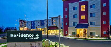 A multi-story hotel with a sign reading "Residence Inn by Marriott" and a landscaped entrance area.