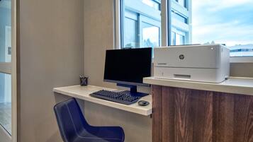Ein moderner Schreibtisch mit Computer, Tastatur, Maus und einem HP-Drucker.