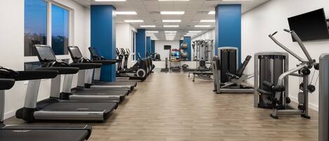 Une salle de sport équipée de tapis de course, de ballons d’exercice et d’appareils de musculation.