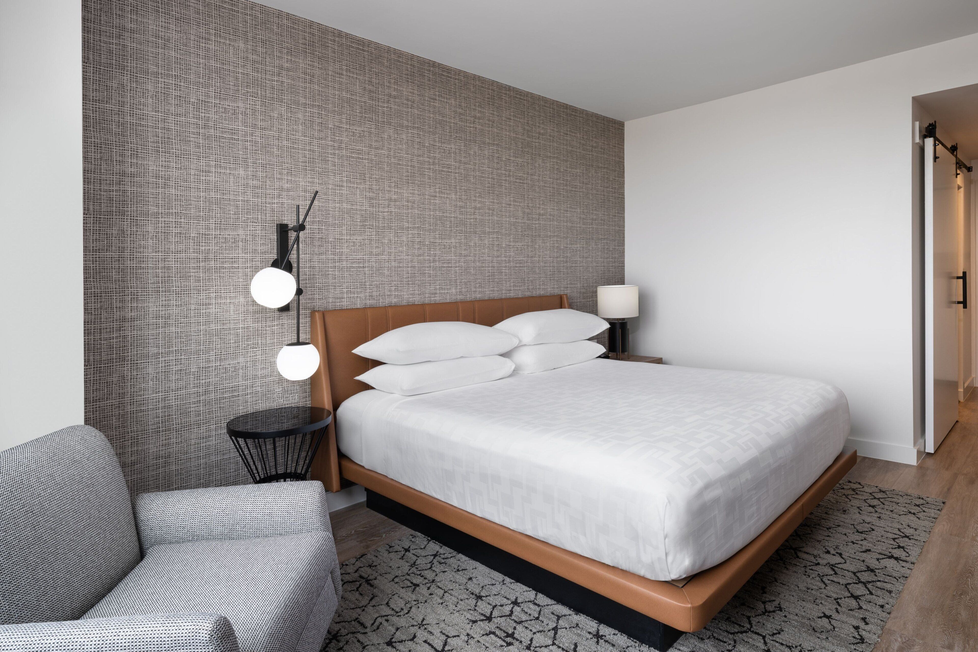 A modern bedroom with a large bed, a round table, and a patterned wall.