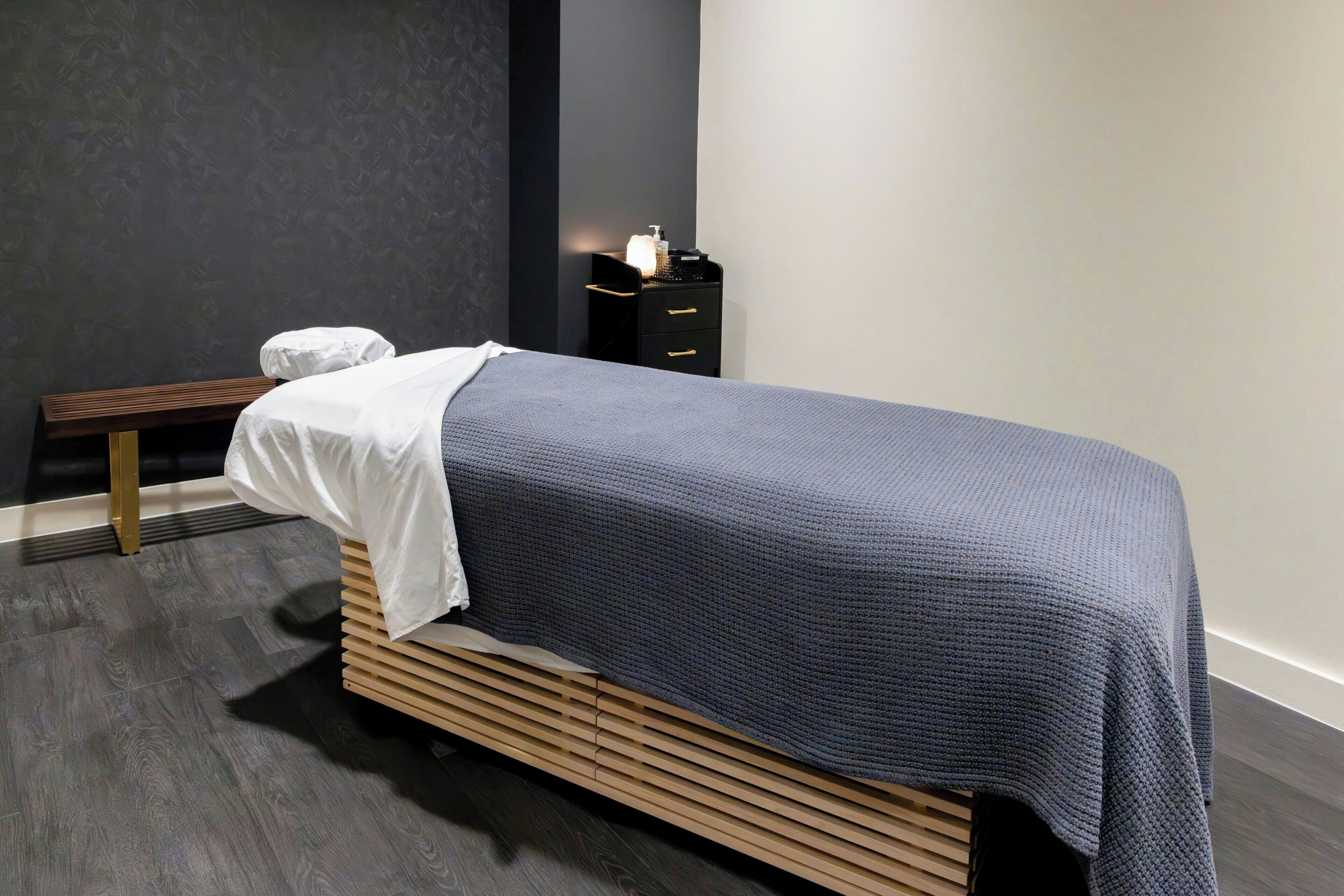 A modern bedroom with a bed, bedside table, and a bench.